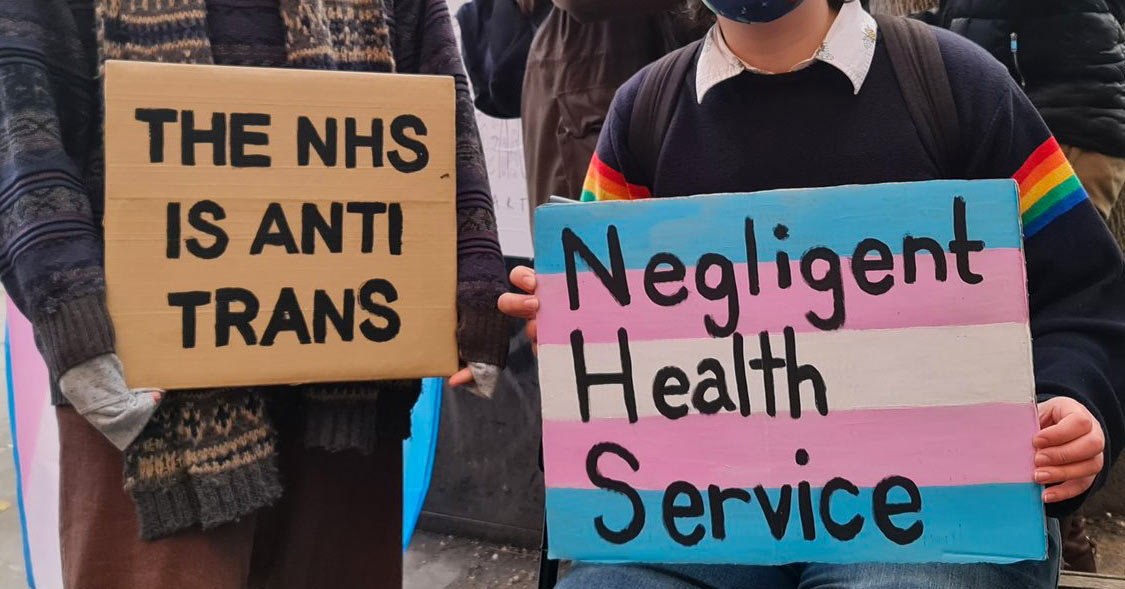 2 placards say "THE NHS IS ANTI TRANS" and "Negligent Health Service"